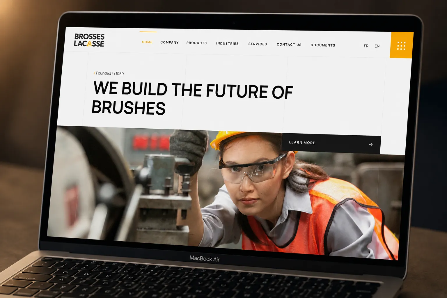 Brosses Lacasse website redesign on laptop, showcasing industrial brush manufacturing and worker.